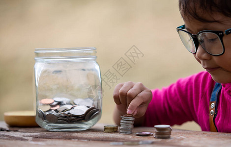 小女孩和堆积硬币储蓄图片
