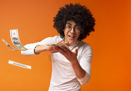 有钱的黑人青年扔钞票橙色工作室背图片
