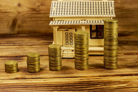 房子模型和成堆的木制背景上的金币物业投资房屋贷款房屋抵押图片