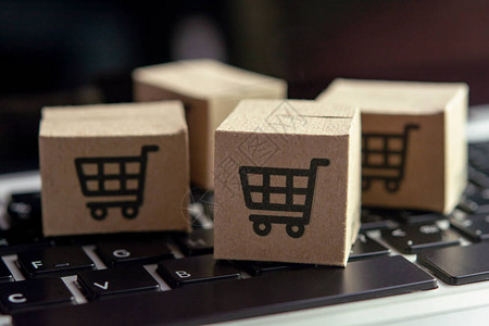 在线购物纸盒或笔记本电脑键盘上带有购物车标志的包裹网上购物服务并提供图片