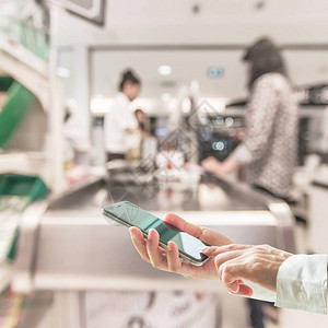 数字生活方式商务人士或购物者使用移动智能手机在超市收银柜台背景图片