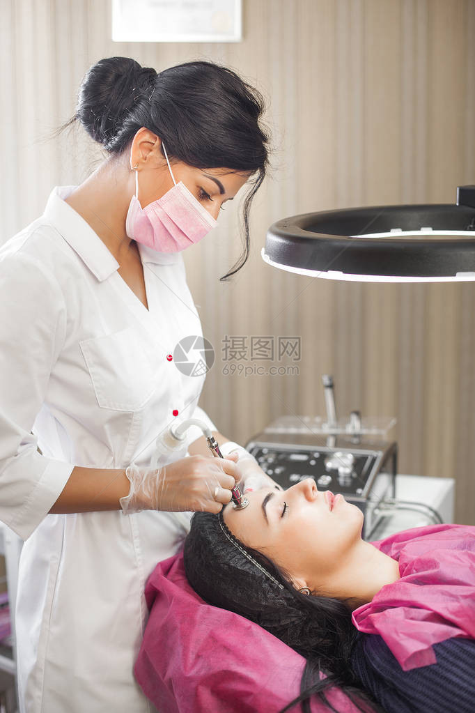 有吸引力的年轻医生对她的客户进行中胚层疗法美容院的女人医生用医疗器械做面部治疗诊所的钻石图片