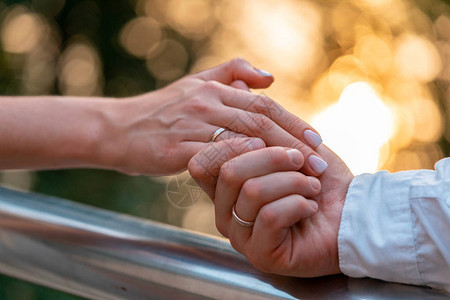 关闭新娘和新郎手上的结婚戒指在夏季或秋季公园户外图片