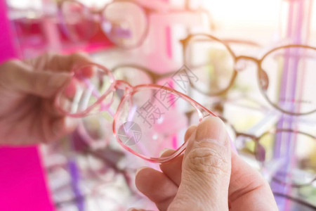 在光学商店选择新光眼镜的妇女的手保健视力和视觉背景图片