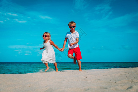 快乐的女孩和男孩跑去海滩图片