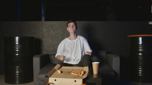 年轻人吃披萨在家看电视在图片