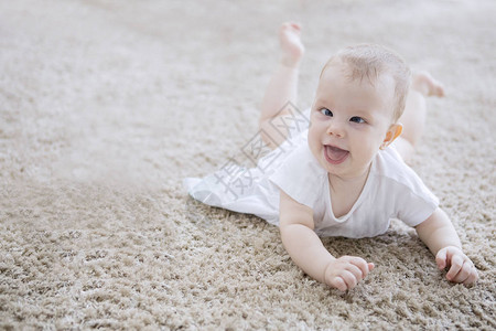 可爱的女婴爬在毛地毯上微笑着对镜头背景图片