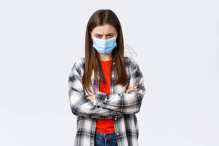 愤怒的年轻疯狂女友戴着医用口罩和格子休闲衬衫图片