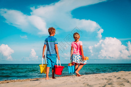 带着玩具的男孩女来到沙滩家庭度假图片