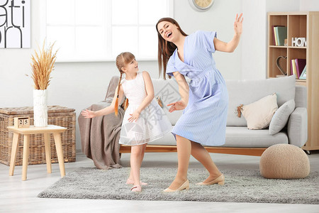 快乐的母亲和她的小女孩在家跳图片