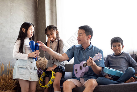 父亲与女儿和子一起玩音乐在客厅放松时图片