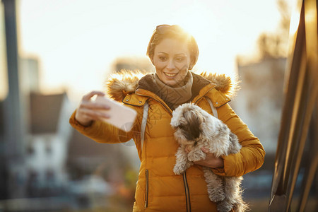 美丽的年轻时装女郎正和可爱的宠物狗在街上共度图片