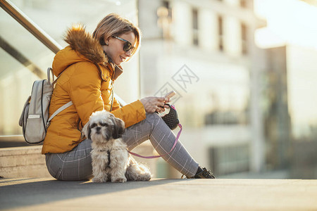 美丽的年轻时装女郎正花时间和可爱的宠物狗一起在城里街上玩图片