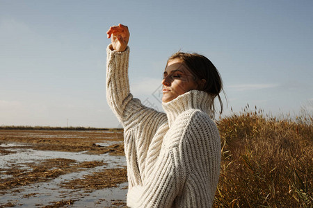 年轻女子穿着温暖的毛衣在冬季海滩图片