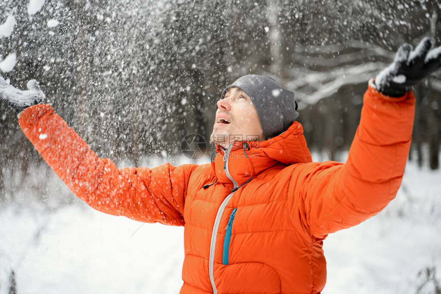 微笑的男人在冬季森林中玩乐和玩雪游图片