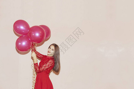 穿着红裙子的快乐而美丽的女人拿着气球情人节生日妇女节周年纪念日图片