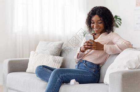 在家智能手机上微笑黑女孩的短信图片
