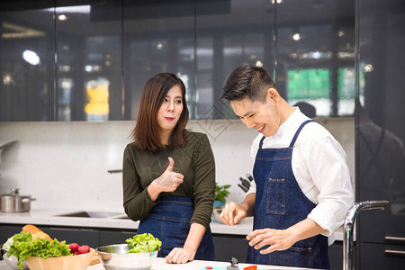 夫妇在厨房为男朋友切菜年轻夫妇正在厨房帮忙切菜亚洲夫妇一起在厨房做饭女背景图片