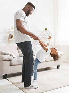 黑爸教小淘气女儿在家跳舞女孩靠父亲的脚和玩得开心图片