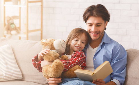 年轻爸在家的周末给小女儿读童话故图片