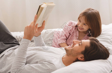 年轻男人读书给小笑的女儿看书图片