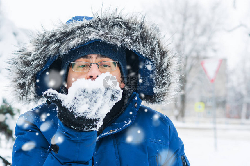 男人手里拿着雪吹着它图片