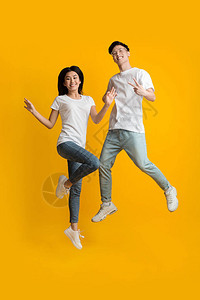 兴奋的亚裔时装狂欢快乐在黄色工作室图片