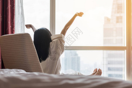轻松生活方式的亚洲女早上醒来在酒店图片