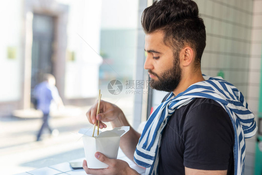 工作休息期间在咖啡馆吃面条的正派年轻时尚男子图片