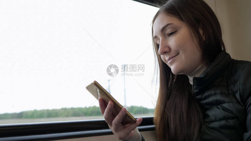 年轻的黑发女旅行者的肖像正在智能手机上看东西图片