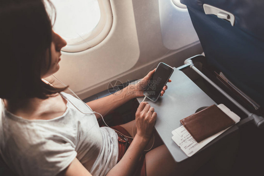 乘飞机旅行的女人坐在飞机上手里拿图片