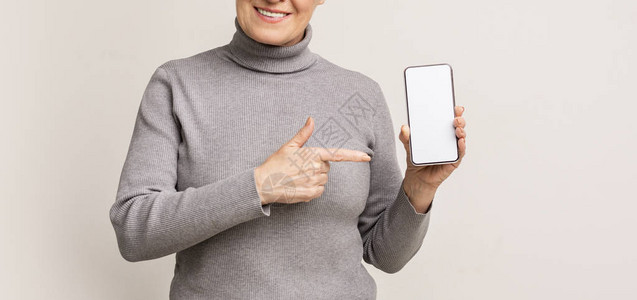 看这里老年妇女展示空白的智能手机屏幕和图片