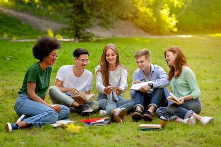 快乐的大学生们用智能手机在户外休息图片