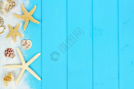 蓝色木质背景中沙子贝壳和星鱼的夏季侧边界图片