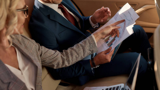 财务计划两个穿着经典服装的商务人士坐在车里分析图表经营理念图片