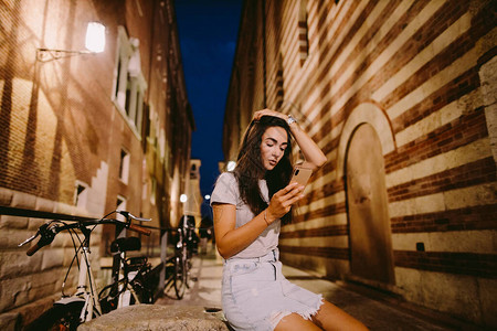 女人晚上在户外使用智能手机图片