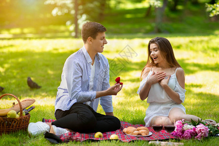 浪漫的年轻人在公园野餐时向他惊讶的女朋友求婚图片