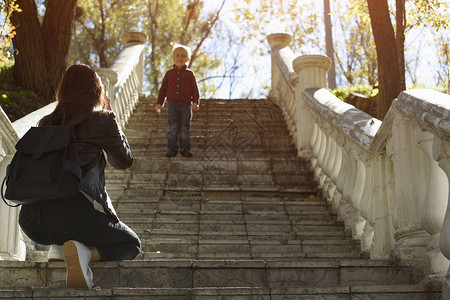 男孩从楼梯上跳到母亲身边在公园图片