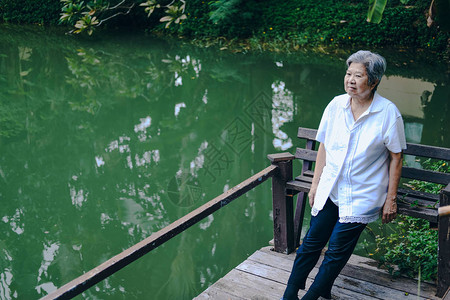 老妇人在池塘边休息亚洲老年女在户外放松高级图片