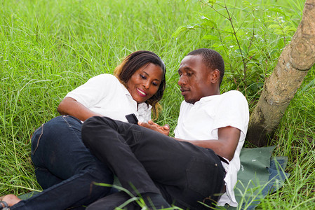 幸福的情侣躺在绿色草地上笑同时使用图片