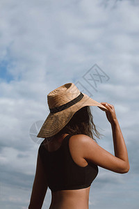 有色人种女孩戴着帽子和在炎热的夏日蓝天背景上摆姿势图片