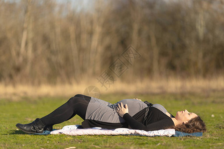 孕妇仰卧在大自然户外的草地上图片