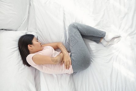 睡在家中卧床期间患上月经腹部痛症的亚洲妇女图片