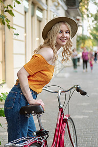 穿着帽子的迷人笑脸金发女孩快乐地看着镜头仰着城市街道上图片