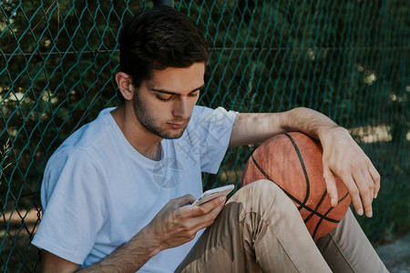 男孩在户外用篮球看手机图片