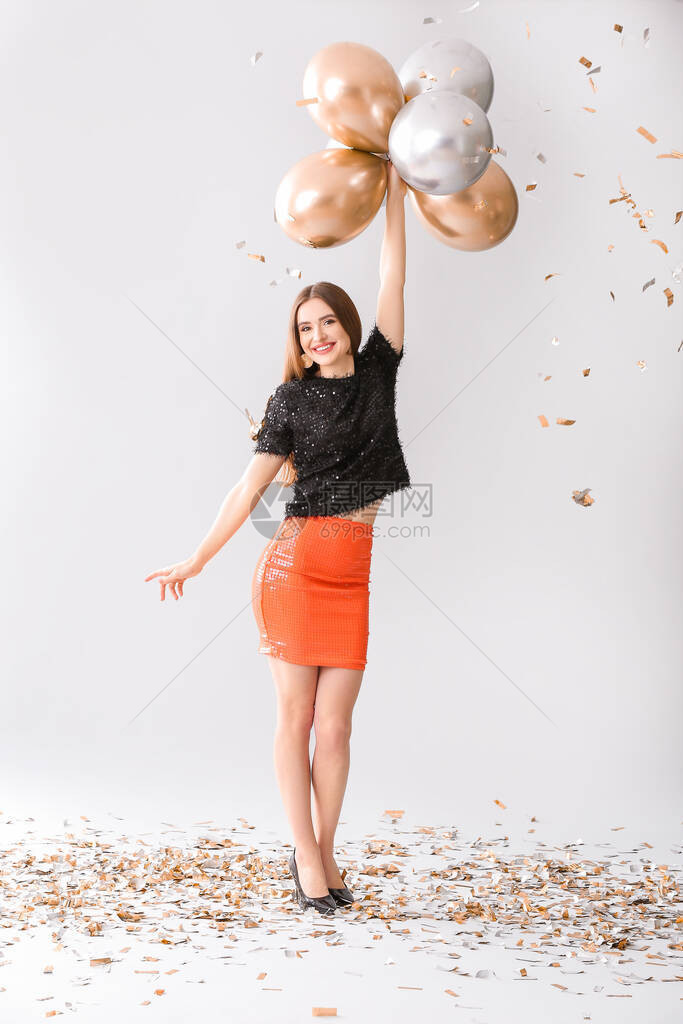 快乐的年轻女子带着灰色背景的气球图片