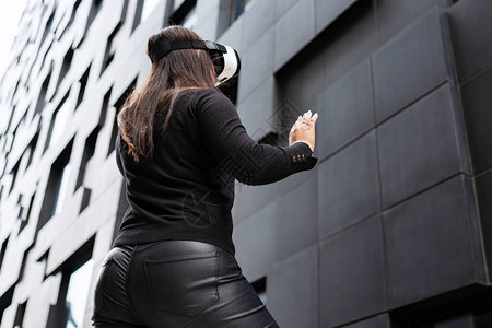 一位戴着虚拟现实技术眼镜和黑色衣服的敬业女背影图片