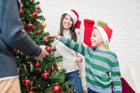 和父母一起在家里装饰圣诞树的小图片