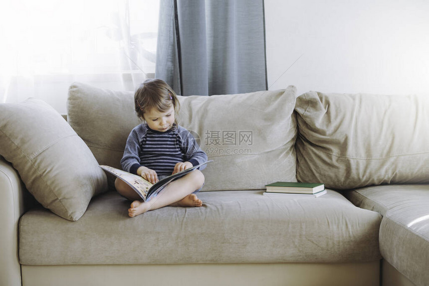 小姑娘在家看沙发上的书远程教育数字解毒术图片