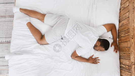睡得很快的非洲人躺在家里卧室的舒适床上图片